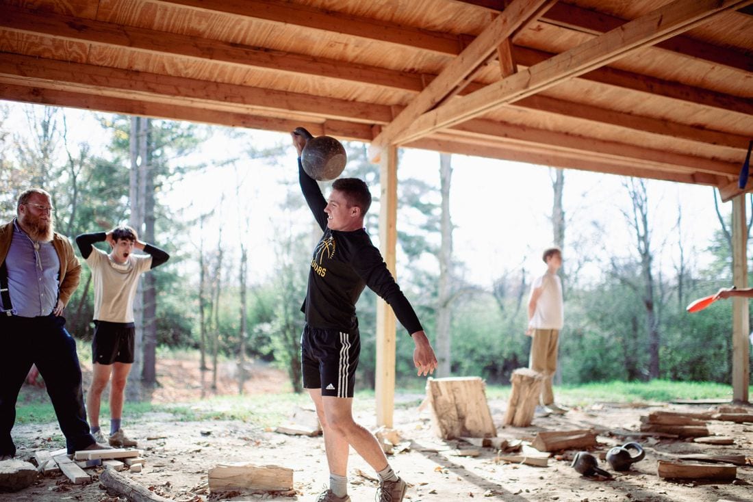 Student pressing a kettlebell overhead during strength training